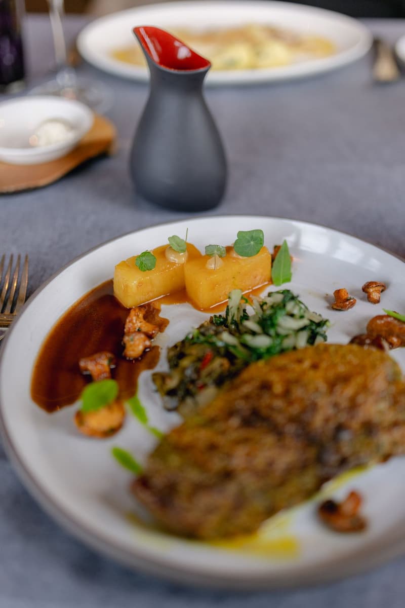 Un piatto di alta cucina impiattato con cura con verdure arrosto e guarnizione di erbe