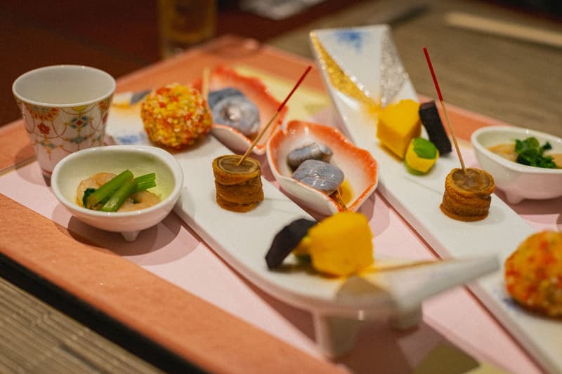 Un plateau de petits plats de cuisine kaiseki japonaise avec brochettes et bols laqués