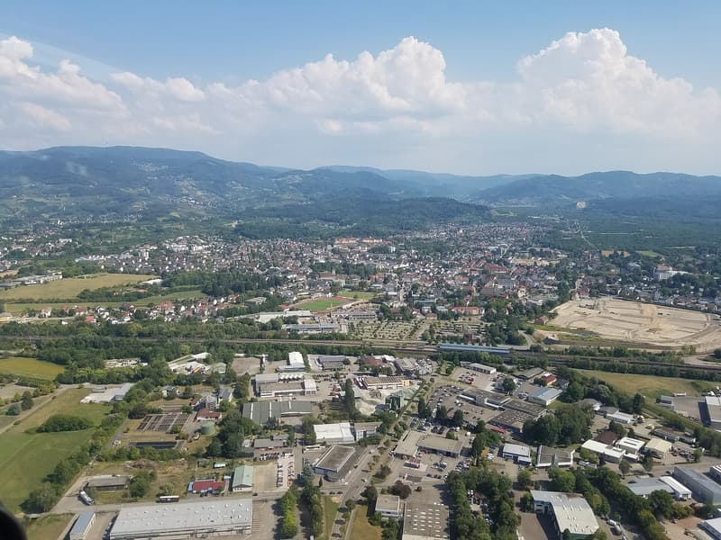 Aerial view of Achern with houses, a railway line and wooded Black Forest hills behind