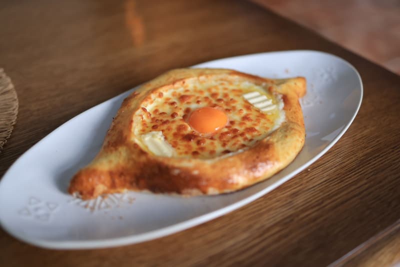 Adjarisches Khachapuri-Boot mit geschmolzenem Käse, Butter und rohem Eigelb