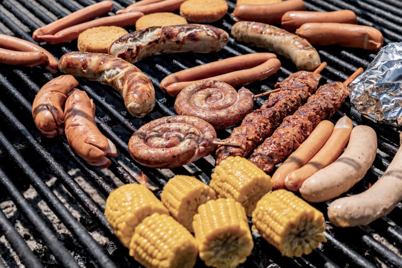 Diverse gegrilde vleessoorten en groenten op een barbecue