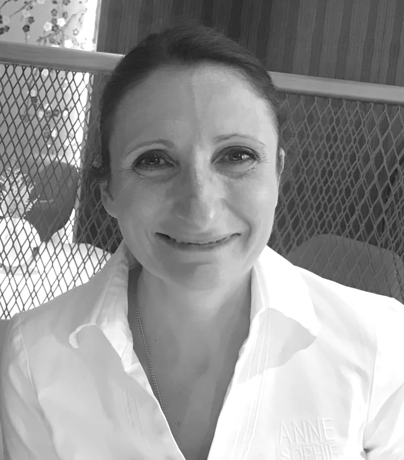 Black and white portrait of chef Anne-Sophie Pic in her white kitchen jacket