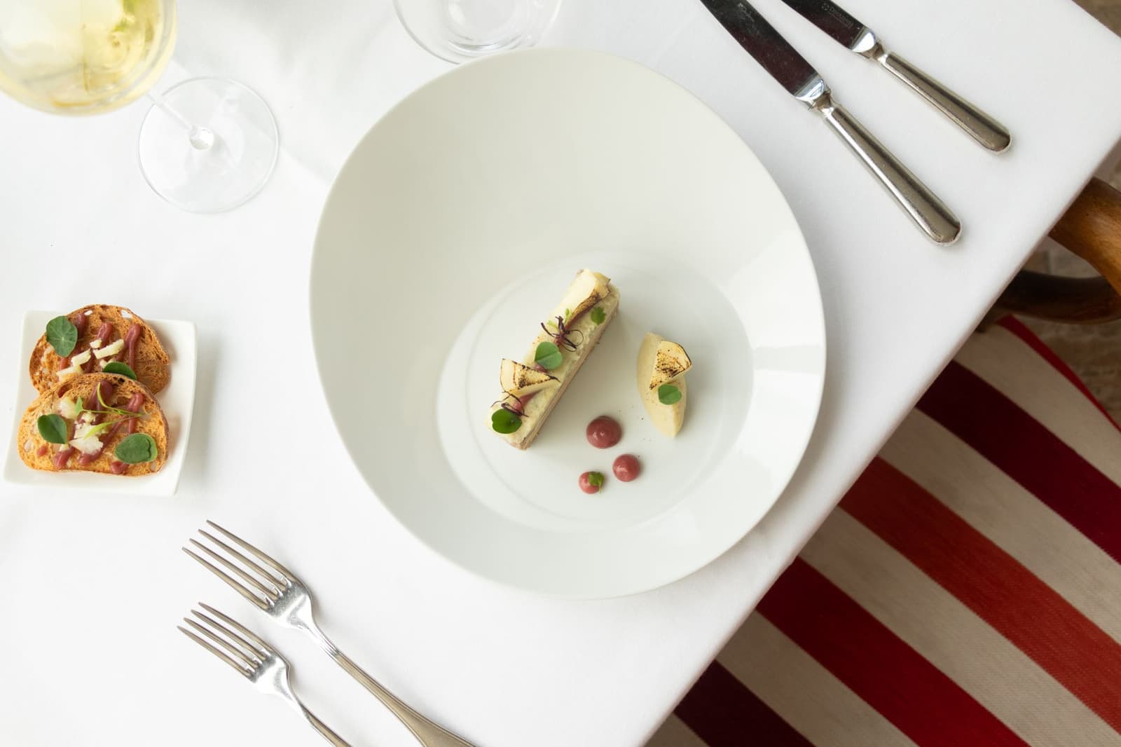Un plat français élégant dressé sur une nappe blanche avec des couverts