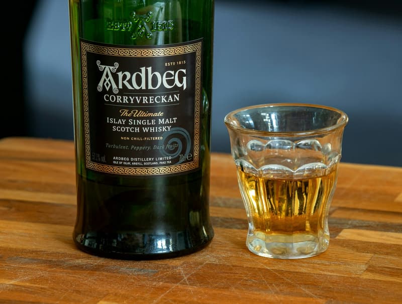 Bouteille de whisky écossais single malt Ardbeg d'Islay près d'un verre rempli sur un bar en bois