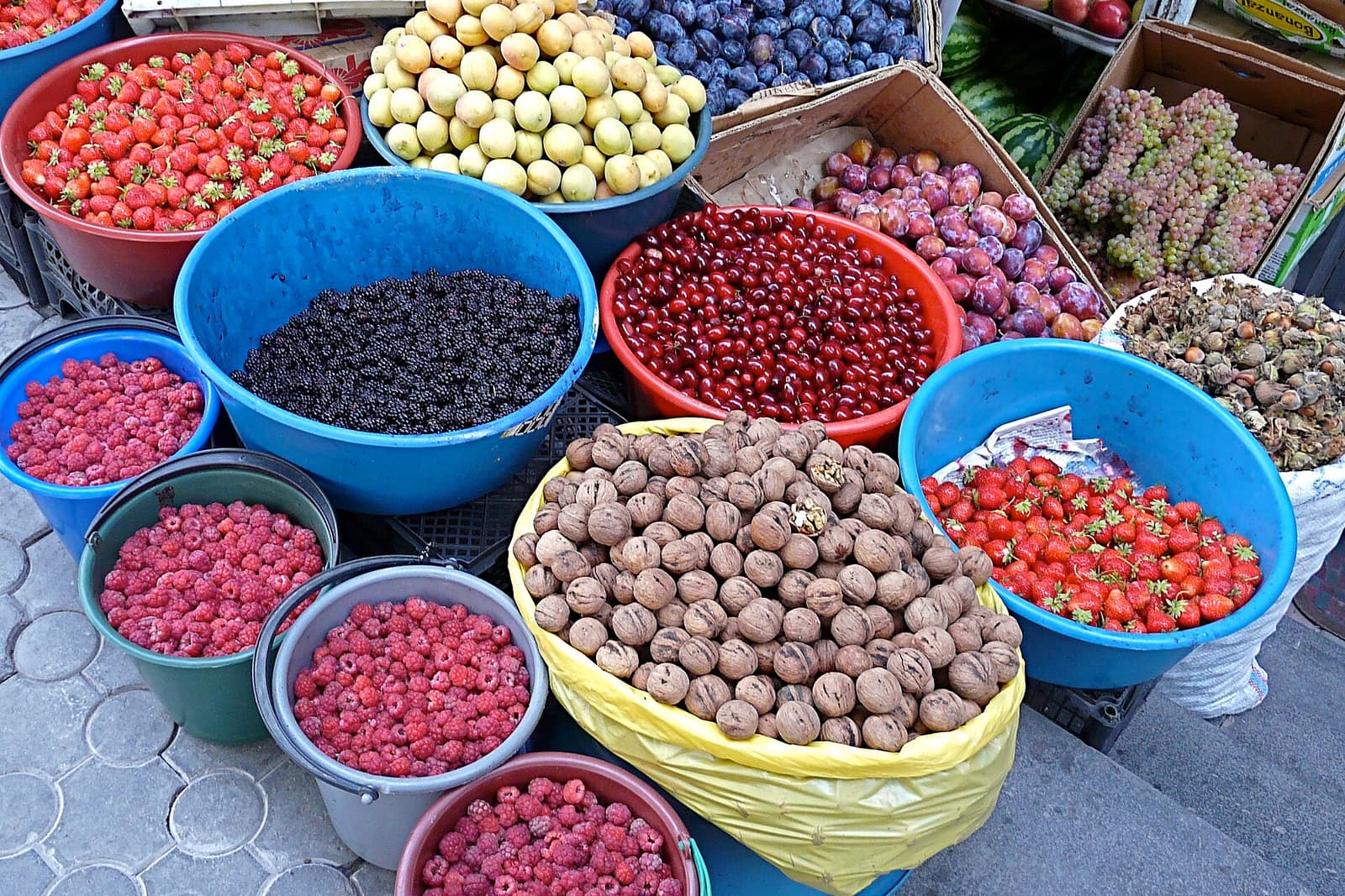 Teilen met abrikozen, aardbeien, frambozen, pruimen en walnoten op een straatmarkt in Jerevan