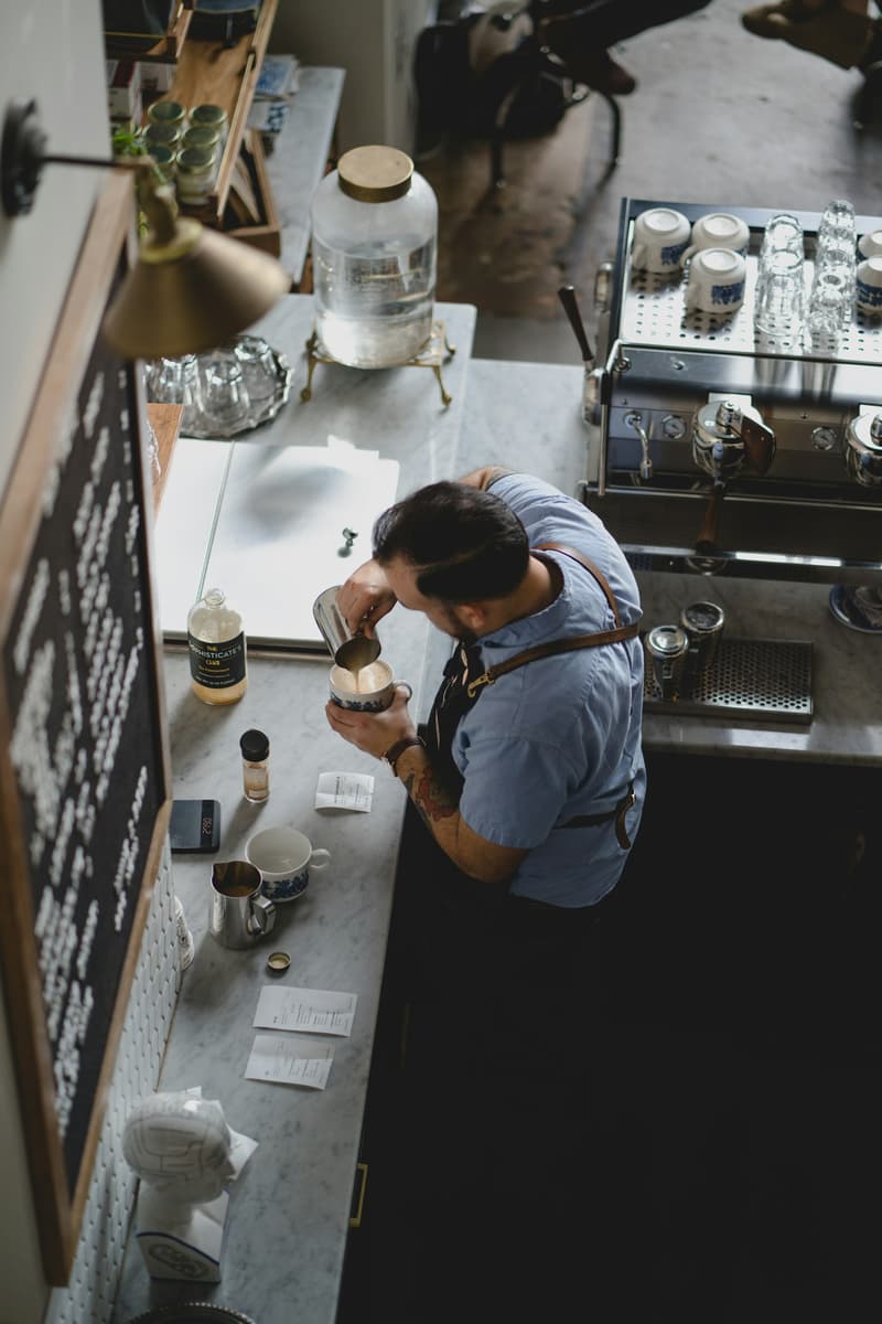 Un barista verse du lait mousseux dans une tasse à espresso sur un comptoir en marbre