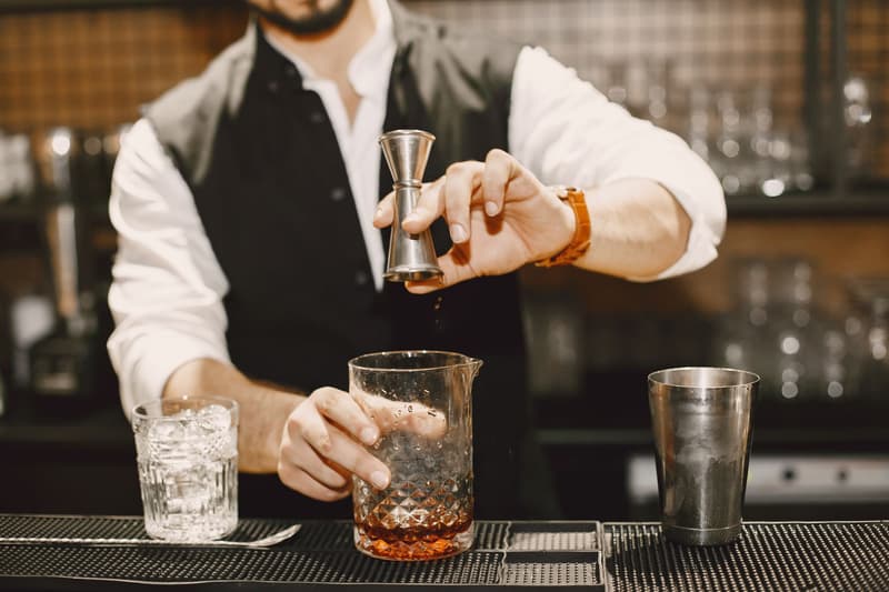 Un bartender misura un distillato con un jigger mentre prepara un cocktail