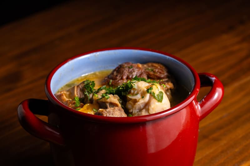 Morceaux de viande braisée dans une sauce au vin rouge, parsemés de persil haché, dans une cocotte rouge