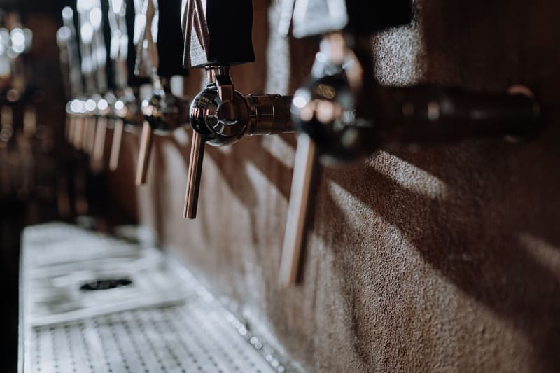 Rangée de robinets à bière chromés le long du comptoir d'une brasserie artisanale