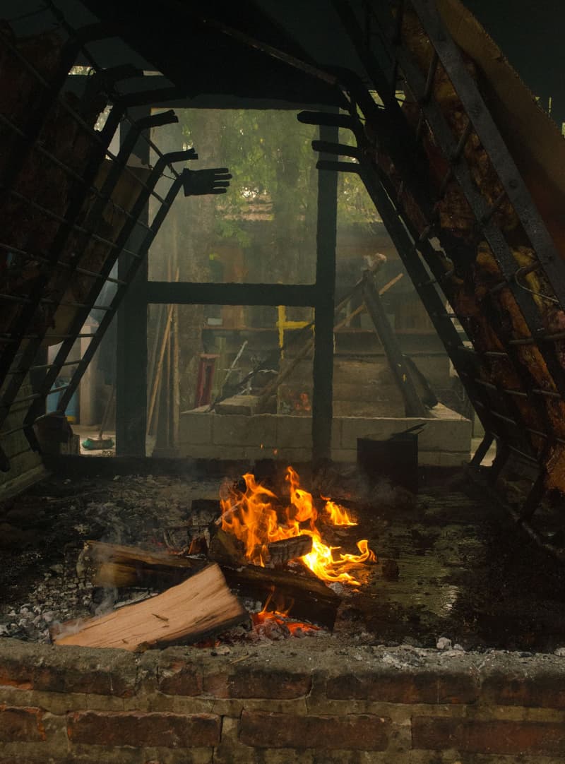 Un fuego de leña abierto asando carne al estilo del asado argentino