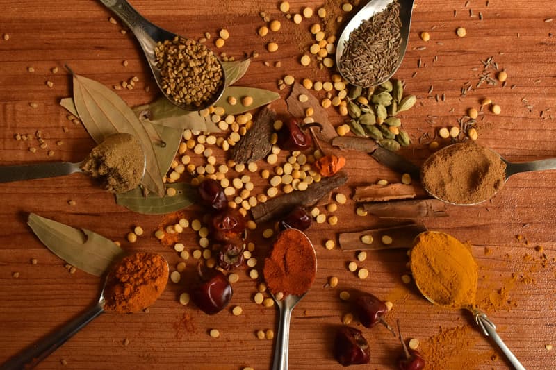 Una vista cenital de coloridas especias indias, guindillas y canela en cucharas de madera
