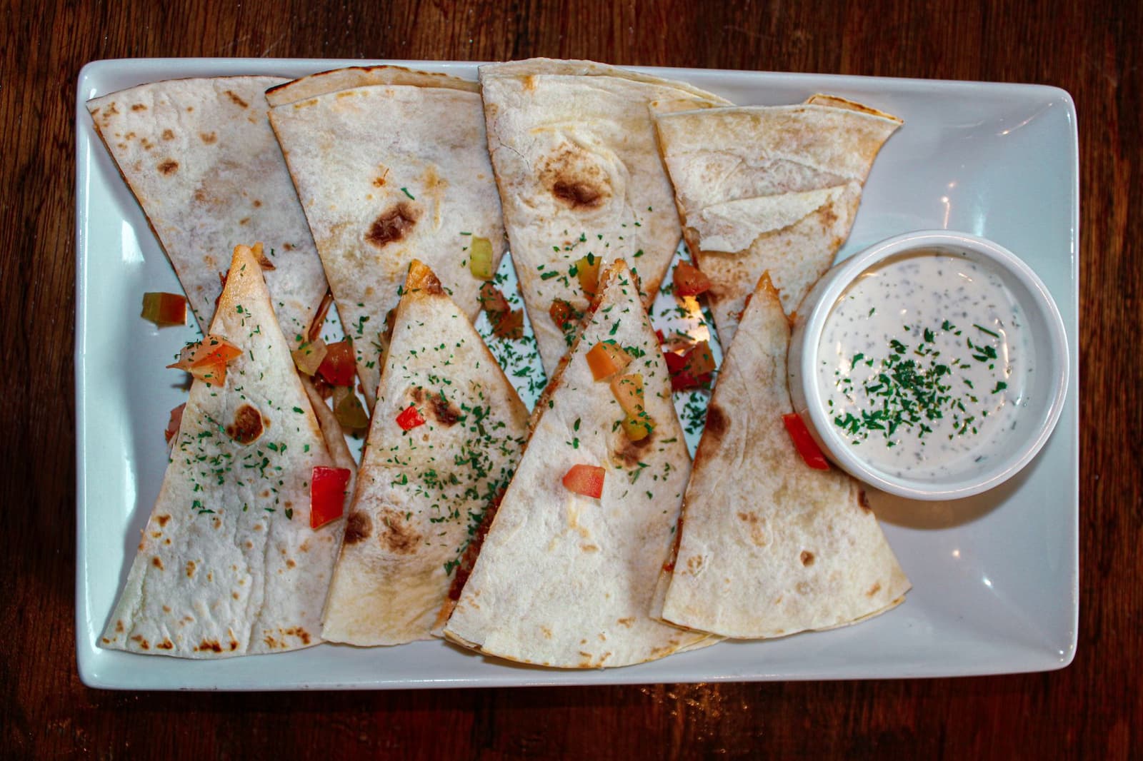 Käse-Quesadilla-Ecken auf einem Teller mit einer Schale cremigem Dip