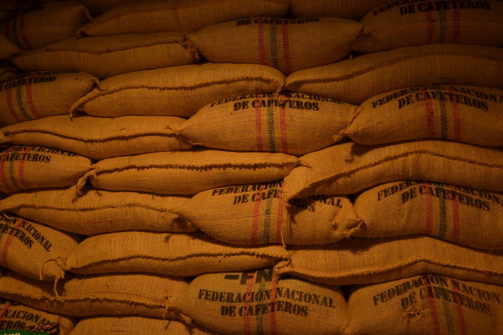 Gestapelte Jutesäcke mit grünen Kaffeebohnen in einem Lagerhaus