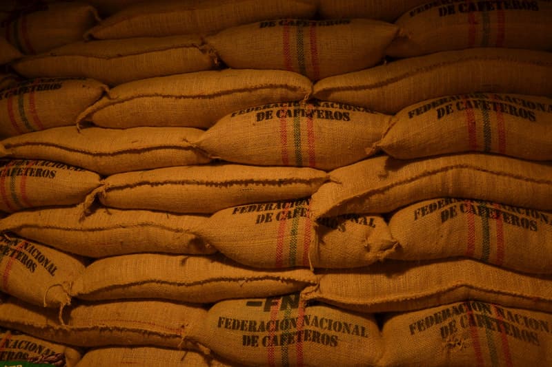 Sacchi di iuta impilati con chicchi di caffè verde in un magazzino