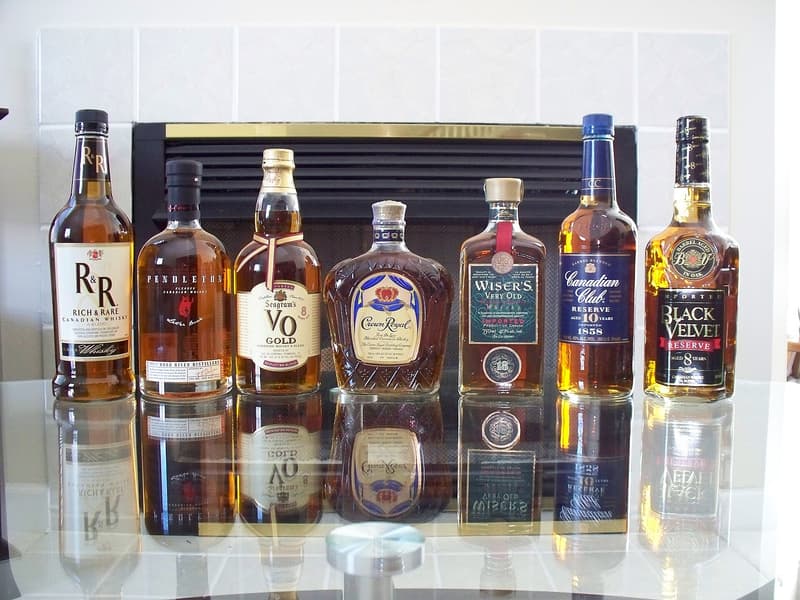 Seven bottles of Canadian whisky, Crown Royal among them, lined up on a glass table