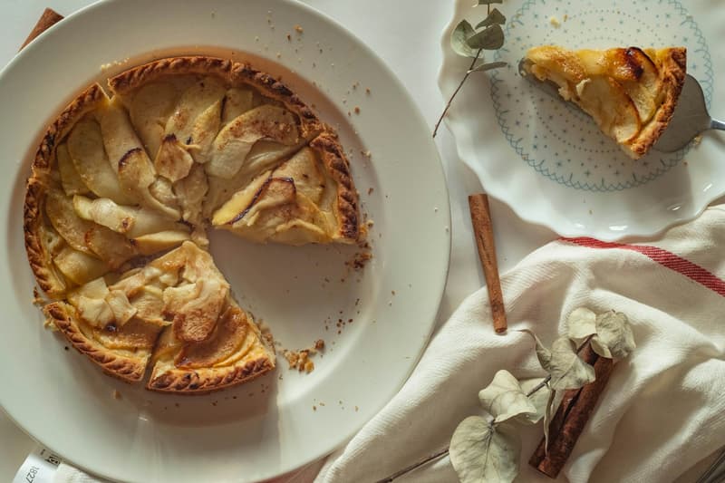 Golden caramelized apple tart with glossy caramel, sliced and served on a plate