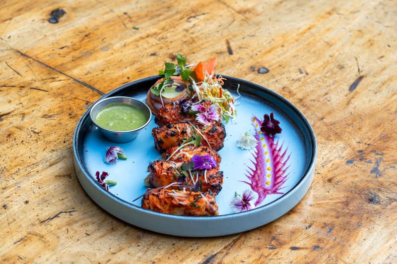 Une assiette de brochettes de fruits de mer tandoori au chutney de menthe et fleurs comestibles