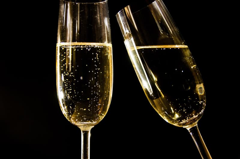 Gros plan sur deux flûtes de champagne remplies de vin effervescent sur fond sombre