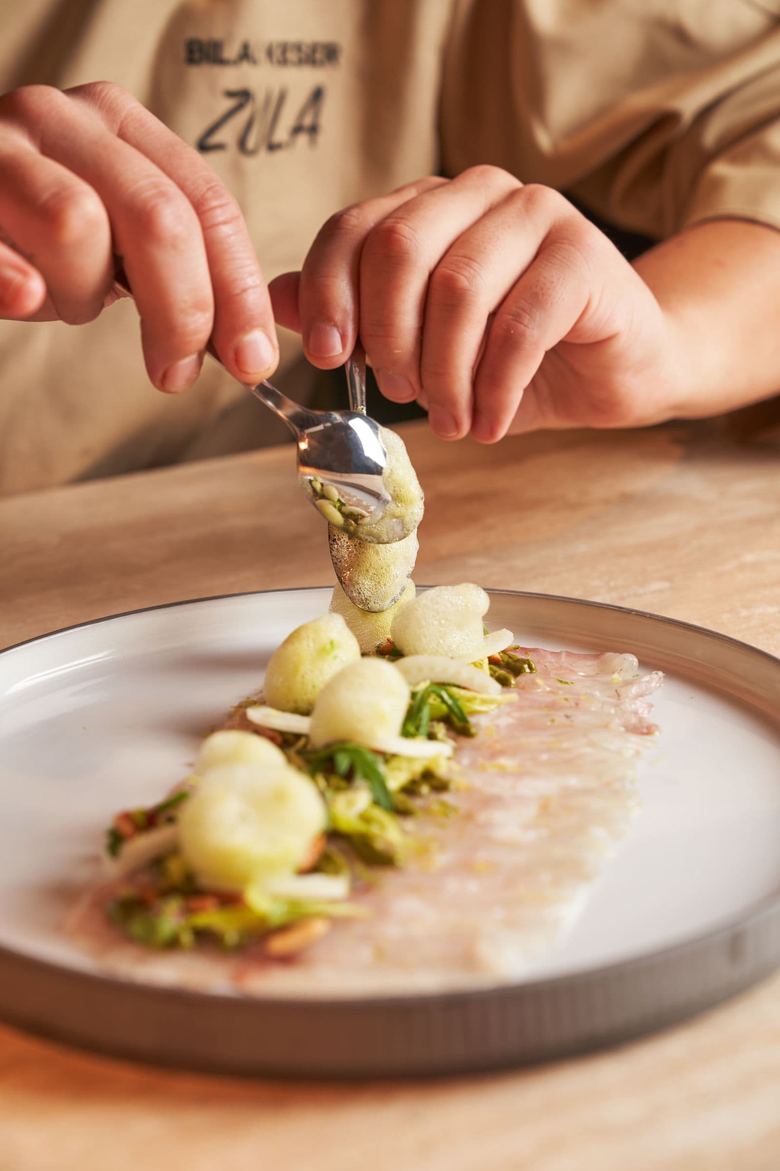 Les mains d'un chef dressant un plat délicat de menu dégustation à la cuillère
