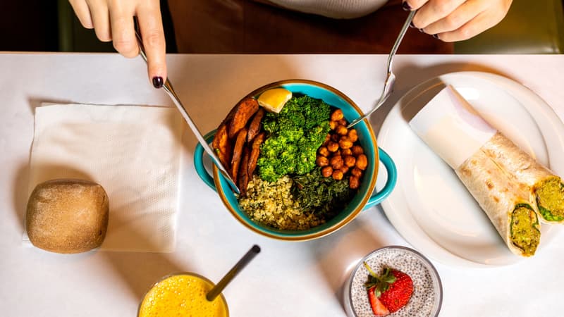Bovenaanzicht van een burrito bowl en een wrap op een restauranttafel