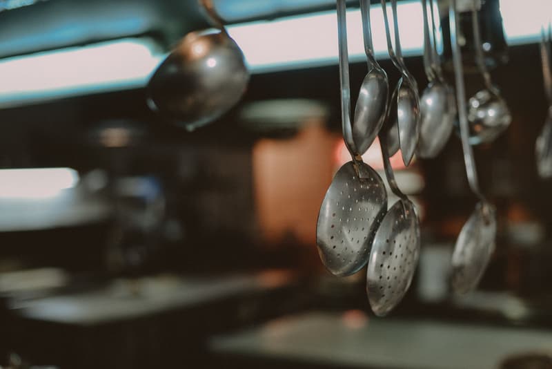 Ladles and skimmers hanging above a restaurant kitchen line