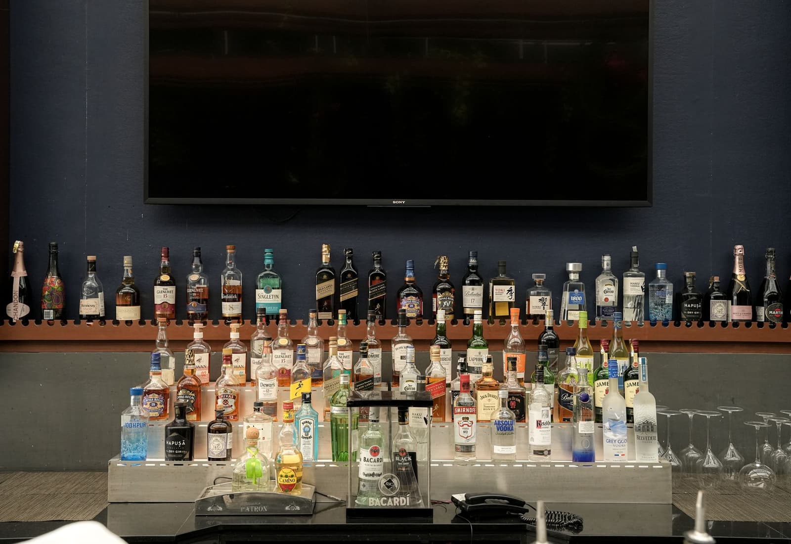 Rijen flessen sterkedrank uitgestald op schappen achter een cocktailbar