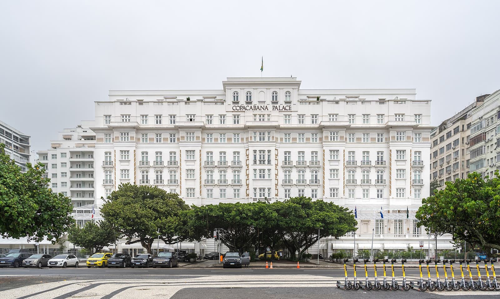 White facade of the Copacabana Palace hotel behind trees on a cloudy day in Rio
