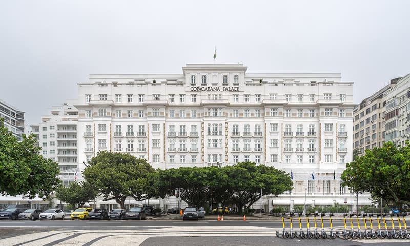 Facciata bianca dell'hotel Copacabana Palace dietro gli alberi in una giornata nuvolosa a Rio