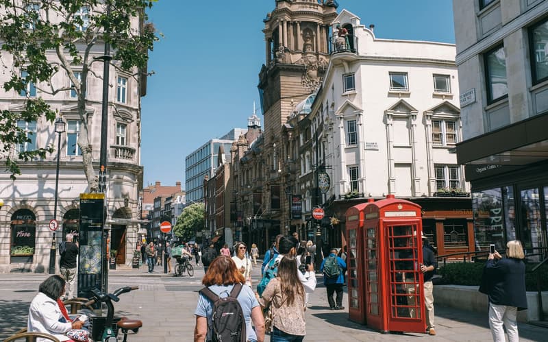 Een drukke straathoek bij Covent Garden met een rode telefooncel