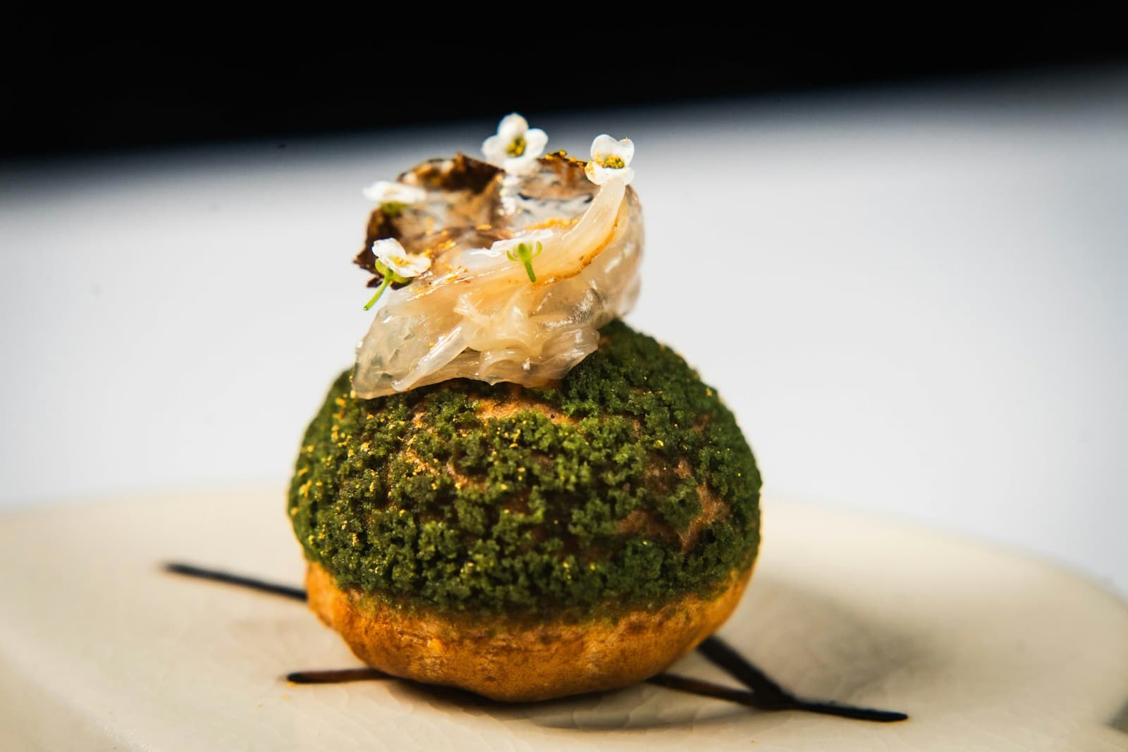 Kreatives Fine-Dining-Häppchen mit essbaren Blüten und Blattgold garniert