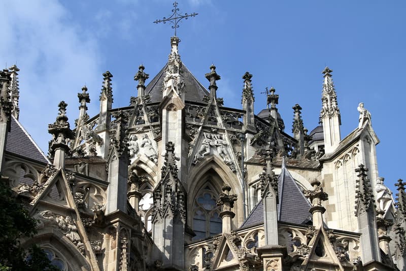 Gothic pinnacles and stone statues of St John's Cathedral in Den Bosch under blue sky