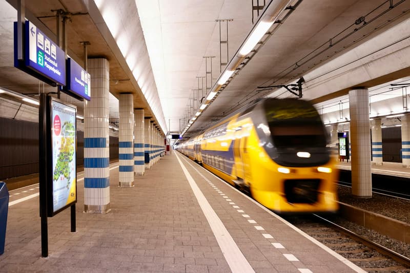 Un train intercity néerlandais jaune et bleu arrivant sur un quai