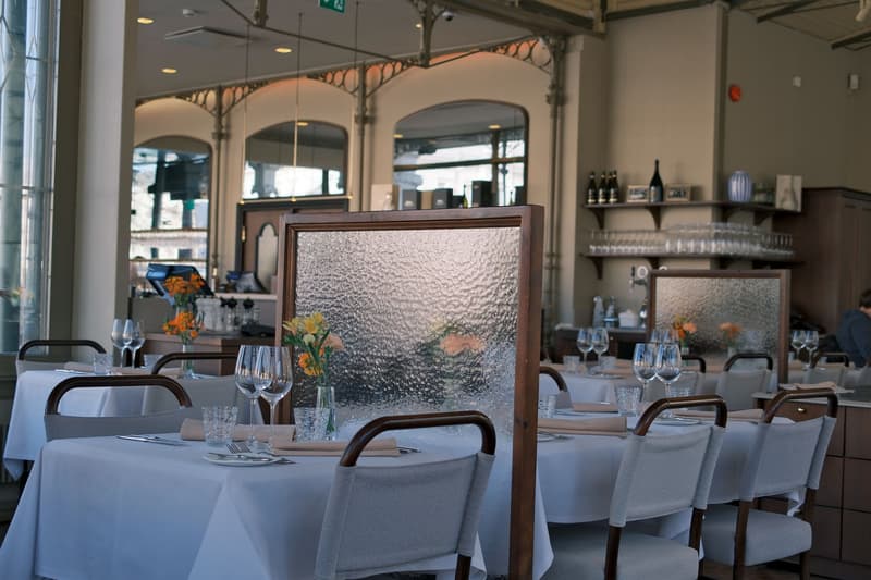 Tavoli apparecchiati con tovaglie bianche, calici di vino e fiori freschi in una sala elegante