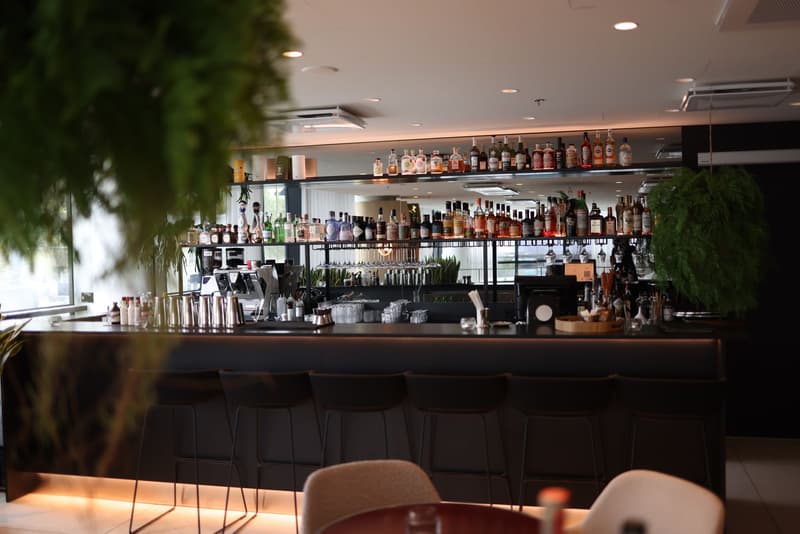 Empty cocktail bar counter with stools and a back bar of bottles, lit and unstaffed