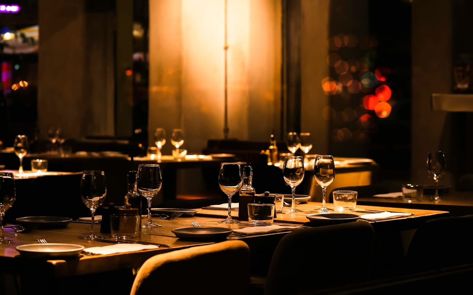 Sala di un ristorante in penombra con tavoli vuoti pronti per il servizio