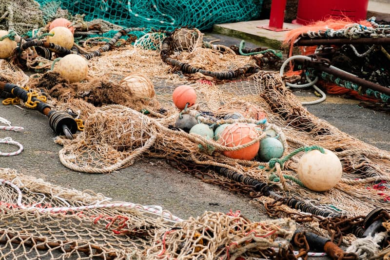 Filets de chalut, flotteurs et chaîne étalés sur un quai
