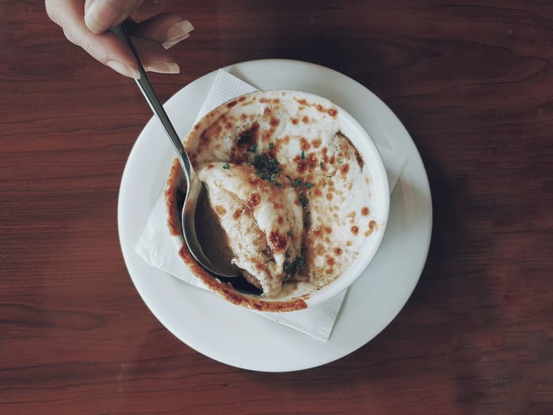 Bol de soupe à l'oignon gratinée avec une croûte de fromage doré percée par une cuillère