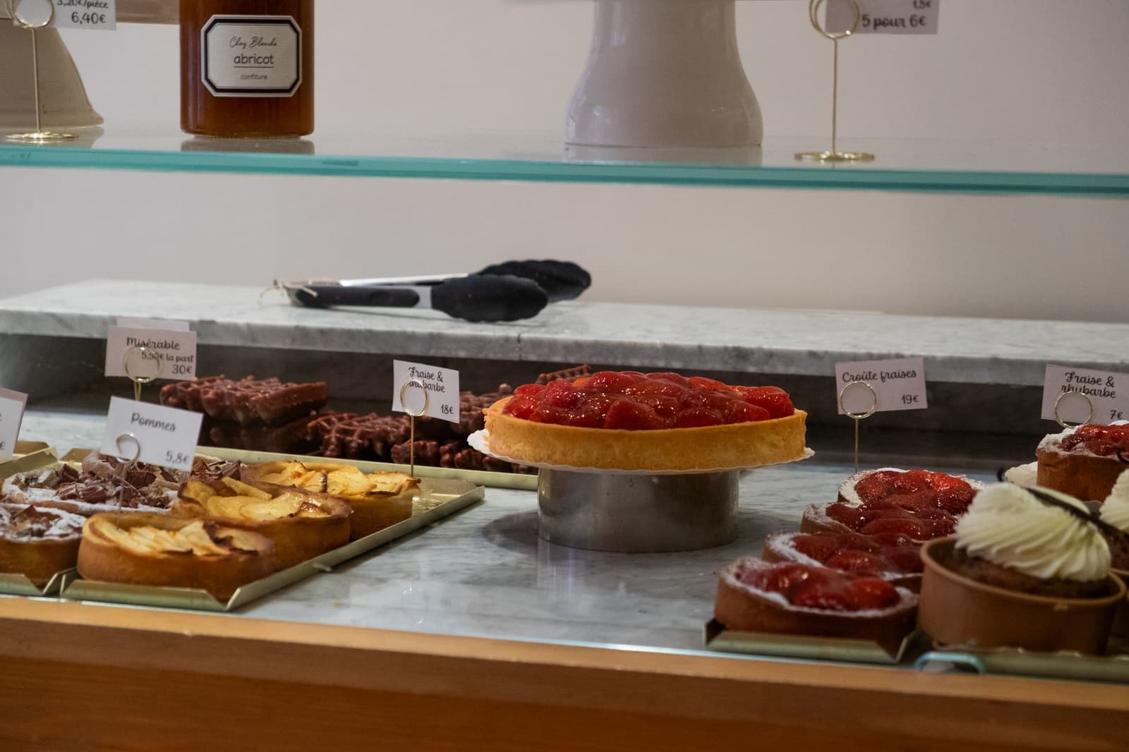 Fruit tarts and pastries displayed in a French patisserie counter with price cards