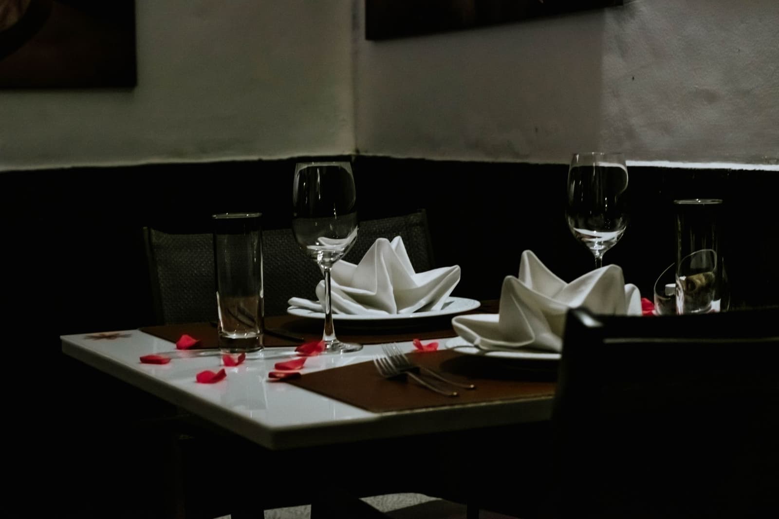 Una mesa íntima de alta cocina puesta para dos con copas de vino y servilletas dobladas