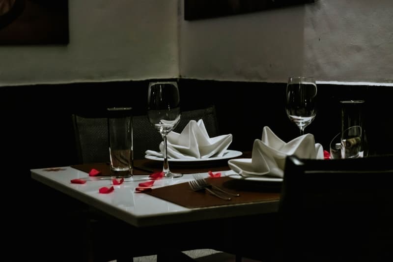 Una mesa íntima de alta cocina puesta para dos con copas de vino y servilletas dobladas