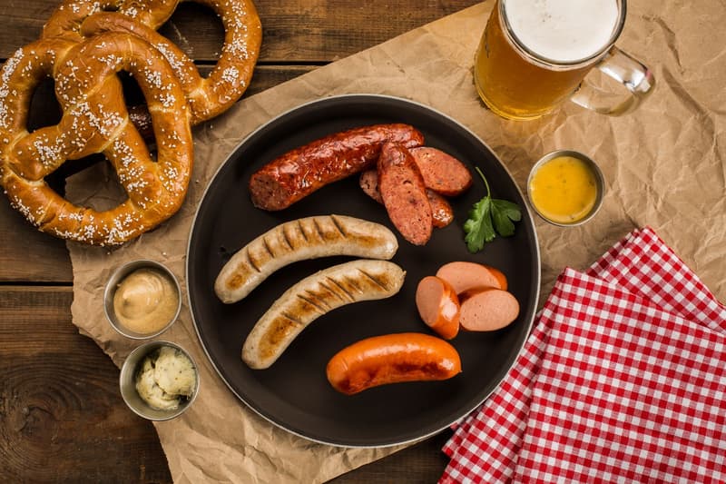 Salsicce tedesche alla griglia, pretzel, senape e birra su un tavolo di legno