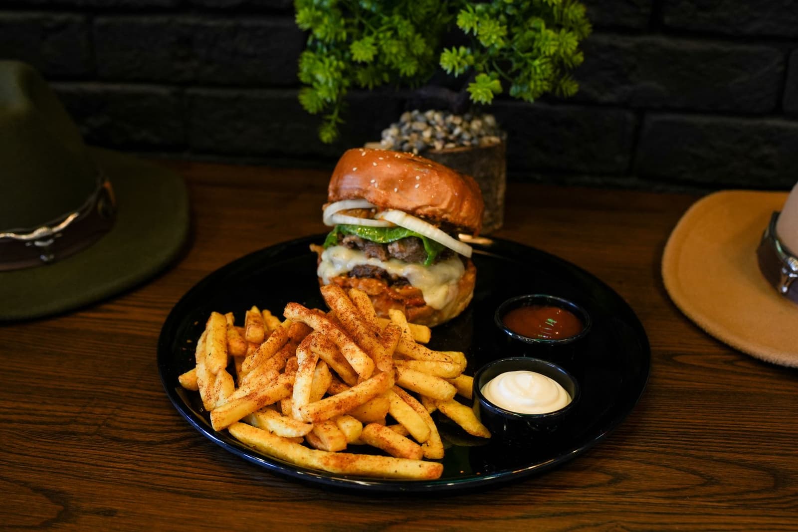 Hamburguesa gourmet con queso fundido y patatas fritas sazonadas en un plato negro