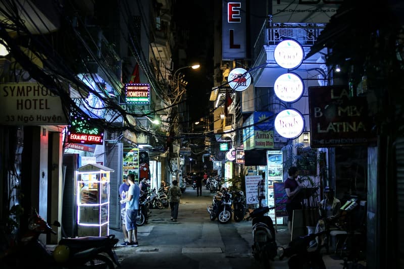 Enseignes lumineuses et câbles enchevêtrés au-dessus d'une rue étroite du Vieux Quartier de Hanoï la nuit