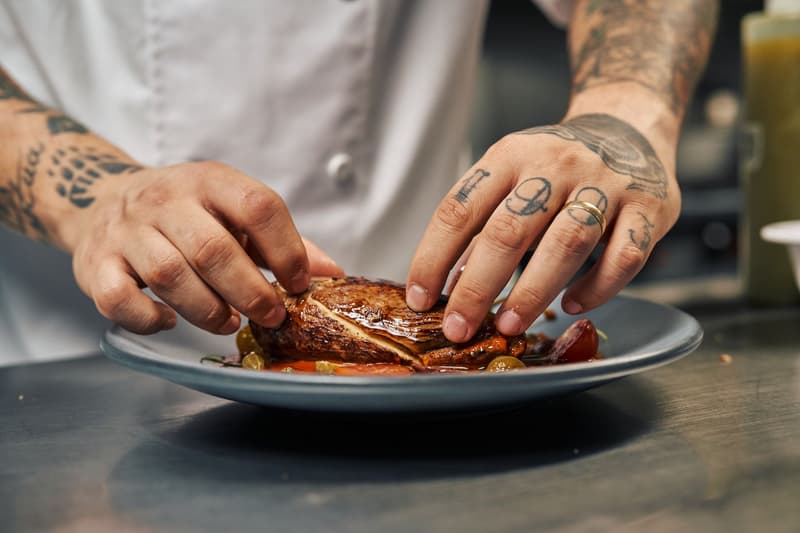 Le mani di uno chef impiattano un piatto in una cucina professionale