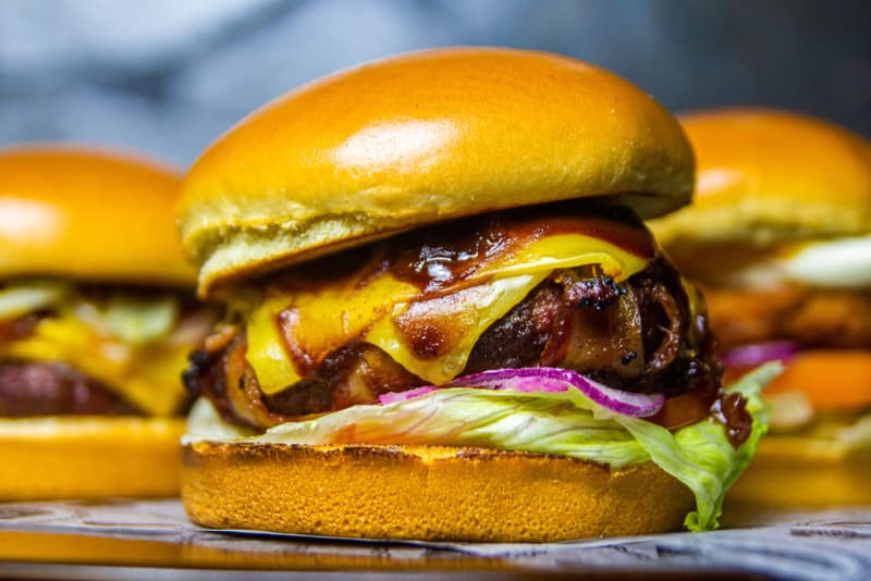 Gros plan d'un smash burger empile avec fromage fondu, bacon et laitue
