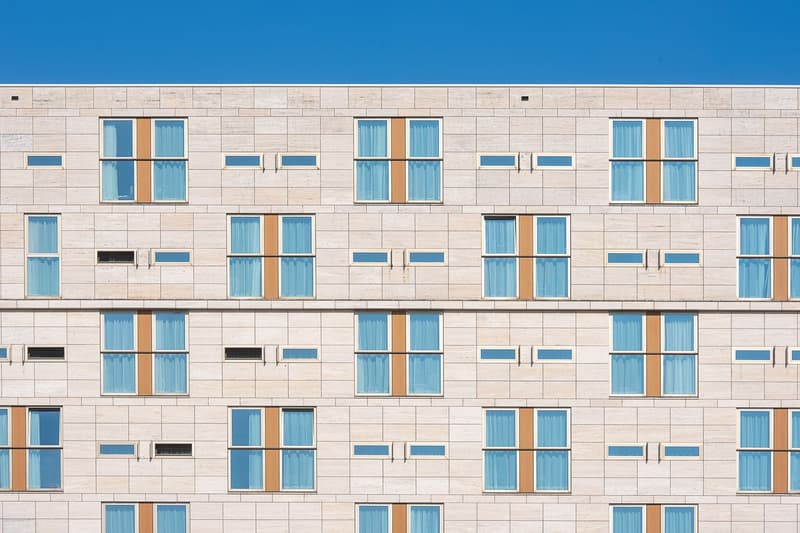 Fachada moderna de un hotel con hileras de ventanas bajo un cielo despejado