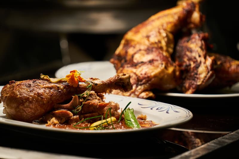 Coscia di pollo arrosto impiattata con erbe e un fiore decorativo, presentazione da alta cucina