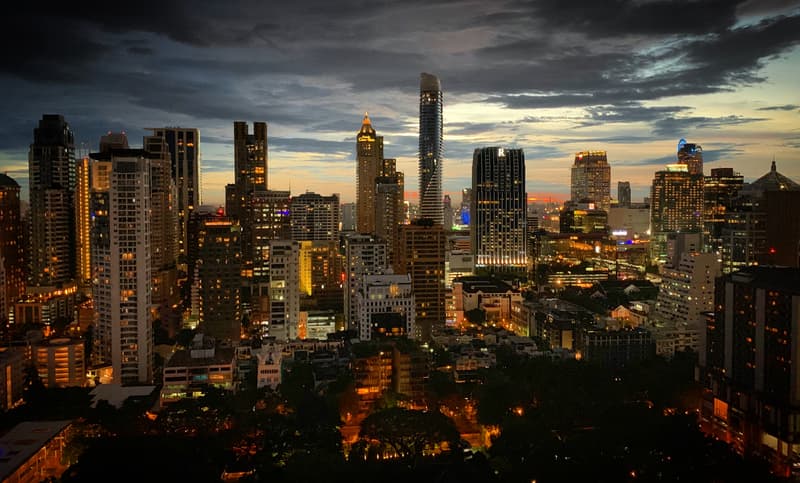 Tours du quartier de Ratchadamri à Bangkok illuminées au crépuscule sous d'épais nuages