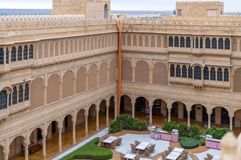 Patio de piedra arenisca de un hotel palacio patrimonial con arcos tallados en Rajastán