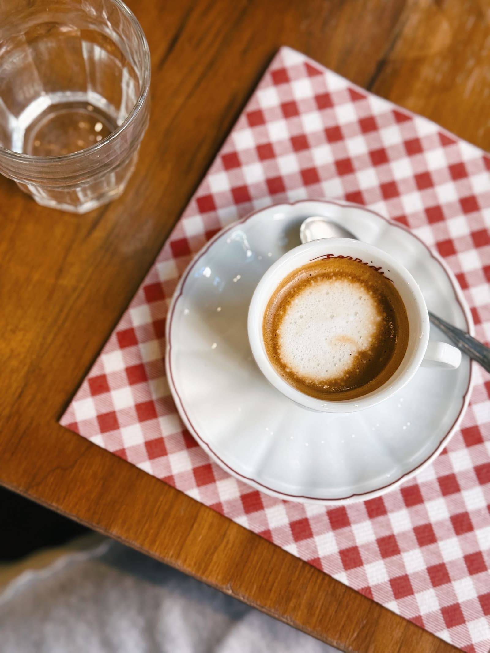 Espresso cup with crema on a red and white checked tablecloth in an Italian cafe